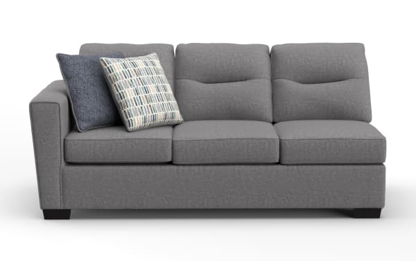 Modern gray fabric sofa with three cushioned seats and backrests, featuring two decorative throw pillows in blue and patterned designs, supported by dark wooden legs.