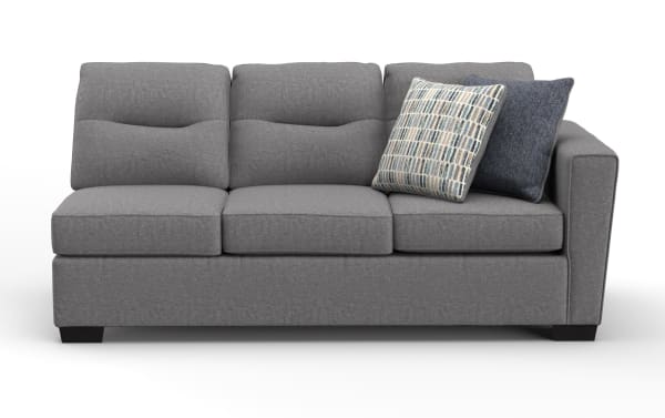 Modern gray fabric sofa with three cushioned seats, tufted backrests, and two decorative throw pillows in blue and patterned fabric, featuring a right armrest and dark wooden legs.