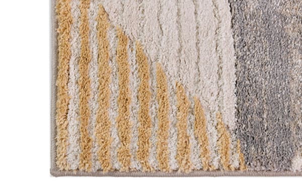 Corner of Margot 5' x 7' multi geometric rug with 1-inch thick polypropylene pile in warm earth tones, featuring textured stripes in beige, tan, and gray.
