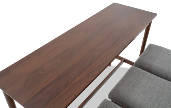 Dark wood rectangular table with smooth finish, paired with grey cushioned stools, showcasing modern dining furniture design.