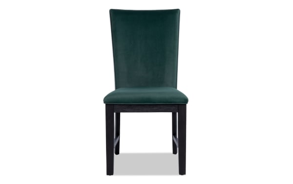 Contemporary Cosmopolitan dining chair with emerald green velvet upholstery, black rubberwood legs, and memory foam seat cushion.