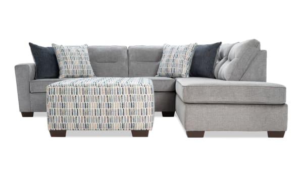 Dylan Slate 112'' 2-piece right arm facing chaise sectional with ottoman in gray polyester fabric. Transitional style with memory foam cushions, four accent pillows, and patterned ottoman.