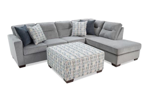 Dylan Slate 112'' 2-piece right arm facing chaise sectional in gray polyester fabric with memory foam cushions, four accent pillows, and patterned ottoman.