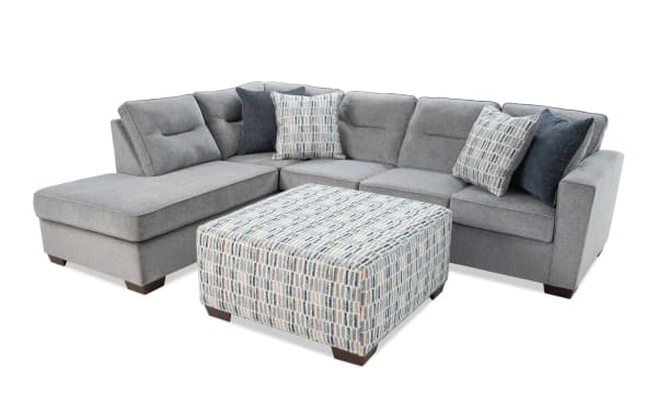 Dylan Slate 112'' 2-piece left arm facing chaise sectional with ottoman in gray polyester fabric. Transitional style with memory foam cushions, four accent pillows, and sturdy patterned ottoman.
