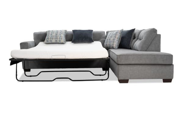 Dylan Slate 112'' 2-piece right arm facing sleeper chaise sectional in gray polyester fabric with queen gel memory foam mattress, four accent pillows, and ottoman. Transitional style with durable Bob-O-Pedic gel mattress and stretch knit cover for comfort and versatility.
