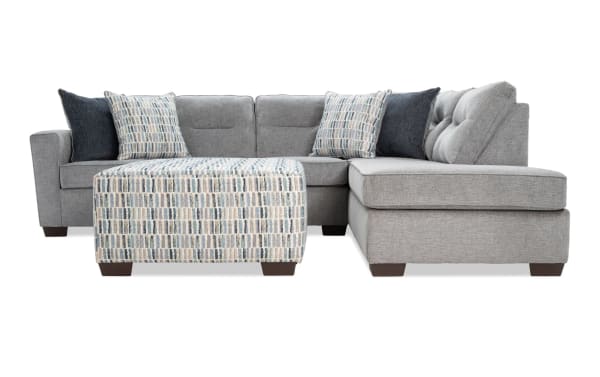 Dylan Slate 112" 2-piece right arm facing sleeper chaise sectional in gray polyester fabric with tufted back cushions, transitional style, includes four accent pillows and patterned ottoman, features Cooling Bob-O-Pedic gel memory foam queen mattress for temperature-regulated comfort.