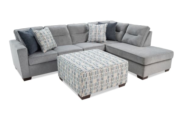 Dylan Slate 112" 2-piece right arm facing sleeper chaise sectional in gray polyester fabric with transitional style, includes cooling gel memory foam queen mattress, four accent pillows, and patterned ottoman.