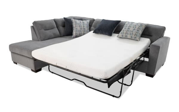 Dylan Slate 112'' 2-piece left arm facing sleeper chaise sectional in gray polyester fabric with queen gel memory foam mattress, four accent pillows, and ottoman. Transitional style with durable Bob-O-Pedic gel mattress featuring temperature-sensitive memory foam and stretch knit cover for comfort and guest use.