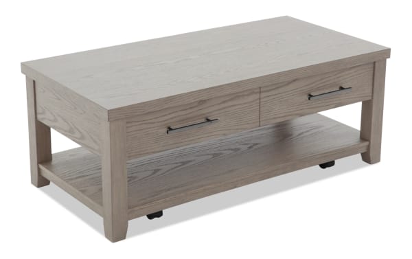 Rectangular gray wood coffee table with two drawers, black metal handles, lower shelf, and four sturdy legs on casters.