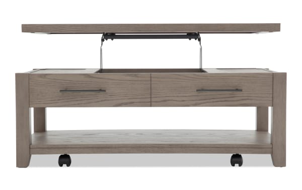 Rectangular light gray wooden coffee table with lift-top mechanism revealing hidden storage, metal handles, lower shelf, and caster wheels.
