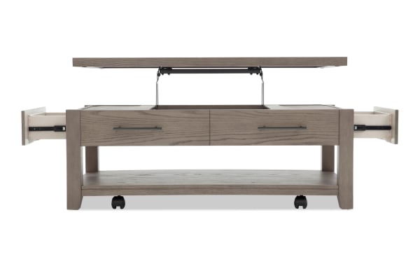 Rectangular gray wooden coffee table with lift-top storage, two side drawers, and lower shelf, featuring black metal handles and caster wheels.
