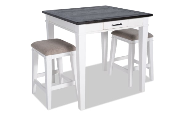 Montana 3 Piece Rustic Counter Height Dining Set with white rubberwood base, distressed oak veneer top, beige upholstered backless stools with memory foam.
