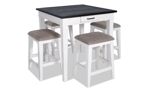 Montana 5 Piece White & Beige Upholstered Counter Height Dining Set with rustic rubberwood and oak veneer top, fabric polyester cushioned stools, and storage drawer.