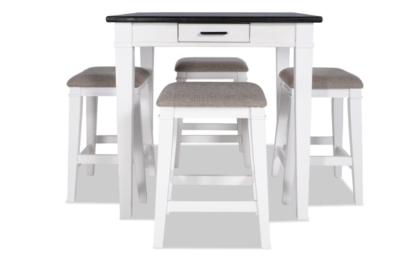 Montana 5 Piece Rustic Counter Height Dining Set with white rubberwood base, distressed oak veneer top, beige polyester upholstered stools with memory foam seats, and built-in drawer storage.