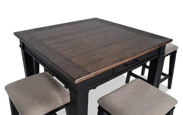 Montana 5 Piece Black & Beige Upholstered Counter Height Dining Set with rustic rubberwood and oak veneer top, black base, fabric polyester beige stools with memory foam cushions, and built-in storage drawers.