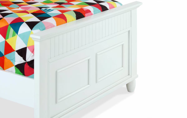 White twin bed from the Spencer 5 Piece Bedroom Set with transitional style, hardwood solids and MDF panel footboard, featuring decorative molding and a colorful geometric quilt.