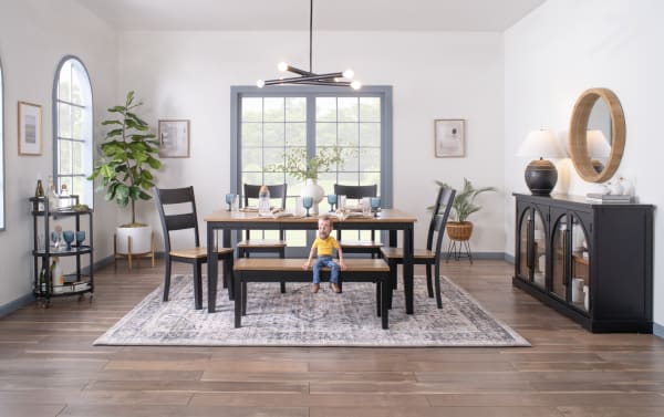 Blake Black & Natural Extendable Dining Table set in cottage style with black hardwood frame, natural wood top, and matching bench on a patterned rug.