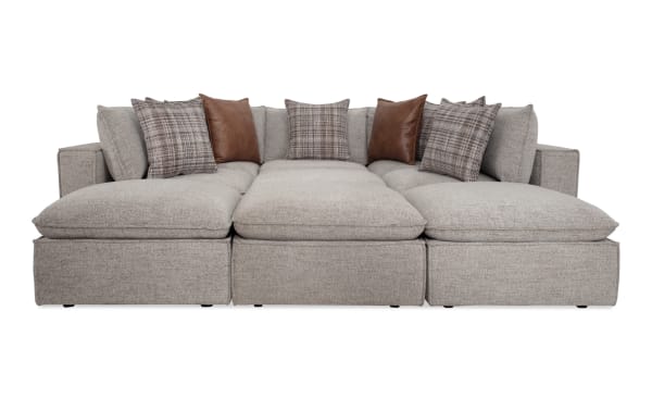 Transitional Infinity Gray 147'' 9-piece modular sectional with gray polyester fabric, 4 ottomans, 3 armless chairs, 2 corners, and mixed plaid and brown accent pillows.