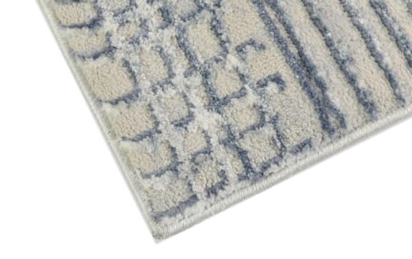 Corner close-up of Linea 8' x 10' cream and charcoal abstract shag rug with soft polyester fabric and geometric pattern for modern home decor.