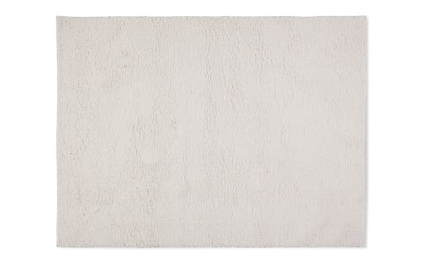 Ivory Ava 5' x 7' shag rug made of plush polyester fabric, featuring a soft, dense pile and neutral beige color for versatile room decor.