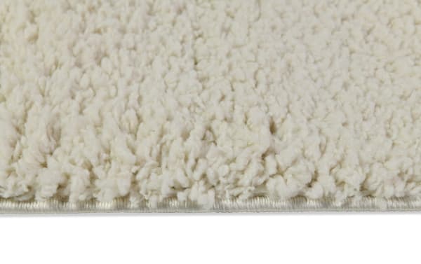 Ivory Ava 5' x 7' shag rug with plush, thick polyester fibers and a soft, neutral beige tone for cozy, stylish home decor.