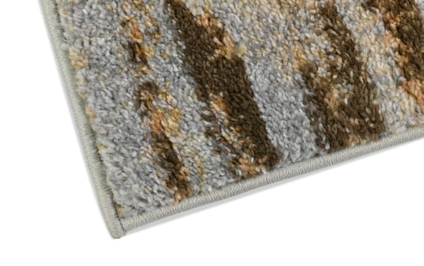 Corner close-up of the Theo 5' x 7' beige and green striped rug showing its medium pile polyester fabric and multicolored pattern.