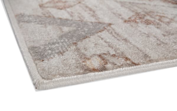 Corner close-up of the Remy 5' x 7' orange abstract rug, featuring soft polyester fabric with warm earth-tone patterns in a transitional style.