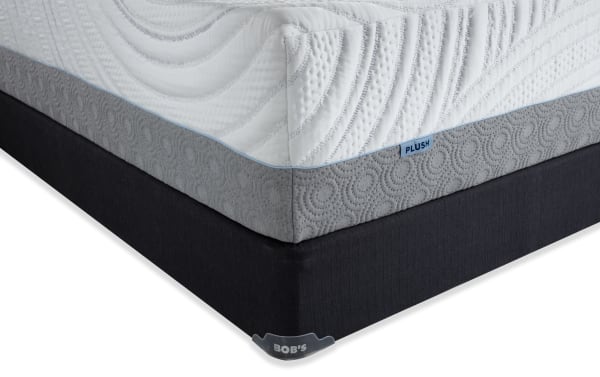 Corner view of Bob’s Twilight 15.5'' Queen Dual Standard Mattress Set in plush, featuring a white quilted top with textured gray side panel and black foundation base, showcasing premium foam layers and gel memory foam for cooling comfort.