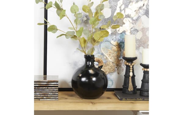 11'' Black terracotta vase with a round body, small handle wrapped in natural fiber, matte farmhouse style, holding green eucalyptus stems, styled on a wooden shelf with black candle holders and decorative book.