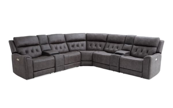 Dark gray sectional reclining sofa with tufted back cushions, plush padded armrests, and built-in console cup holders, designed for living room comfort.