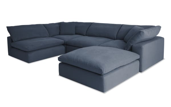 Dream Navy 131'' 5 Piece Modular Sectional in navy blue fabric with two armless chairs, two corners, and an ottoman. Transitional style with polyester and nylon upholstery, featuring oversized reversible cushions with a jersey knit fabric and feather blend topper for customizable living room seating.