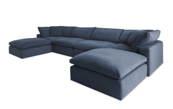 Dream Navy 174'' 6 Piece Modular Sectional in navy blue fabric with two armless chairs, two corners, and two ottomans. Transitional style with oversized reversible cushions in polyester and nylon blend upholstery. Modular design allows customizable living room seating arrangements with cozy jersey knit-like fabric and feather blend topper cushions.