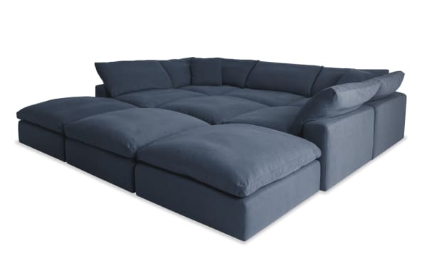 Dream Navy 131'' 9 Piece Modular Sectional in navy blue fabric with 4 ottomans, 3 armless chairs, 2 corners, and oversized reversible cushions.