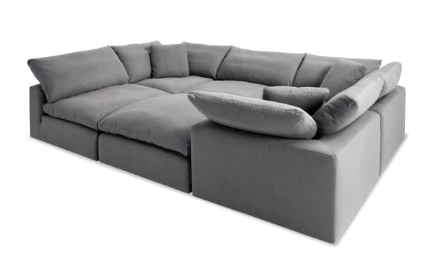 Dream Gray 131'' 6 Piece Modular Sectional in gray polyester fabric with three corners, two armless chairs, and one ottoman. Transitional style with oversized reversible cushions and feather blend toppers for customizable living room seating.