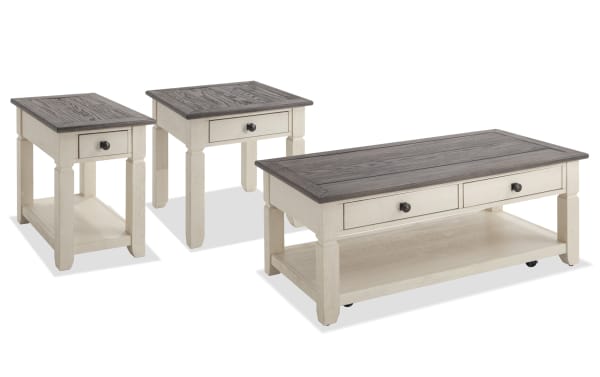 Laurel Entertainment & Occasional two-tone white and brown cottage-style coffee, end, and chairside table set with MDF, rubberwood, acacia veneers, storage drawers, distressed tops, dark hardware, bottom shelves, and casters for easy mobility.