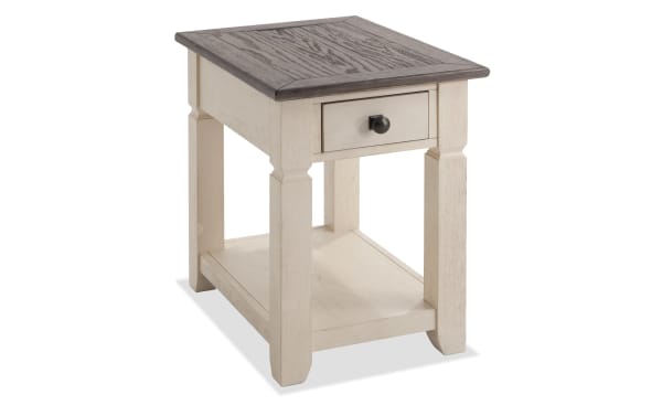 Laurel Entertainment & Occasional cottage-style chairside table in white rubberwood with distressed brown acacia veneer top, storage drawer, and dark hardware.