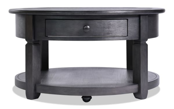 Charcoal round farmhouse coffee table from Laurel Entertainment & Occasional collection, MDF wood with distressed top, storage drawer, and lower shelf.