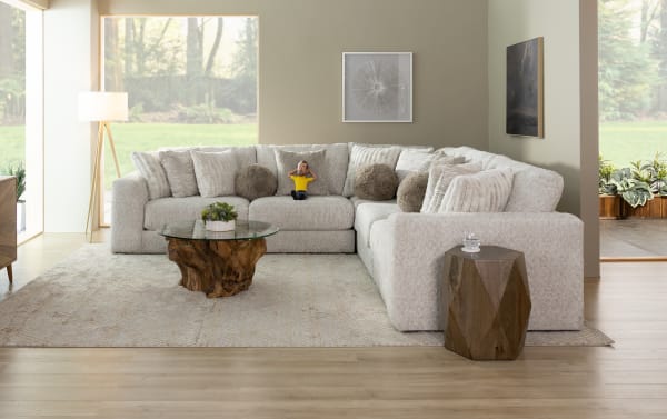 Posh Beige 134" 4-piece modular sectional with plush polyester fabric upholstery, gel-infused memory foam, 13 accent pillows, and storage ottoman in a transitional style living room.