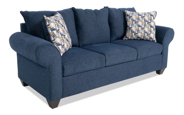 Kylie Navy 92'' transitional sleeper sofa in blue polyester fabric with rolled arms, three seat cushions, patterned accent pillows, and pull-out queen gel memory foam mattress.