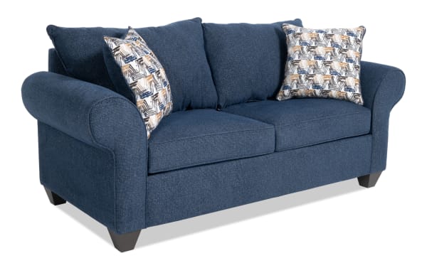Kylie Navy 82'' transitional sleeper sofa in blue polyester fabric with rolled arms, two patterned accent pillows, and plush cushions.