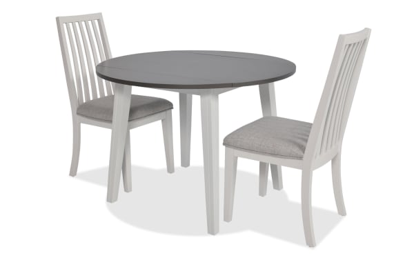 Blake 3 Piece White & Gray Upholstered Dining Set with two gray fabric polyester slat-back chairs and round drop leaf table in transitional style, made of MDF, hardwood, rubberwood, and birch veneers, ideal for small spaces and apartments.