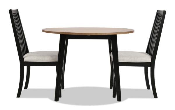 Blake 3 Piece Black & Natural Upholstered Dining Set with two gray polyester fabric cushioned slat-back chairs and a round drop leaf table in black and natural wood finish, featuring MDF, hardwood, rubberwood, and birch veneers in a transitional cottage style for small spaces and apartments.