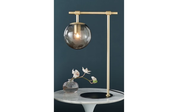 Transitional Ezra Gold Table Lamp with nickel frame and smoky glass globe shade, providing warm ambient light for modern home decor.