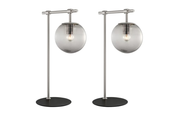 Set of 2 Ezra Nickel Table Lamps with transitional style, nickel frame, black base, and smoky glass globe shades showcasing exposed bulbs for ambient lighting.