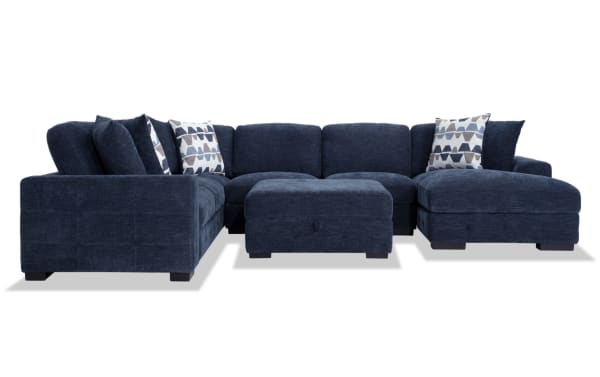 Contemporary Playground Navy 145" 4-piece right arm facing sectional with pop-up sleeper chaise, polyester fabric, hand-tufted cushions, storage ottoman, and oversized accent pillows.