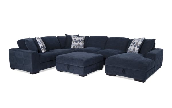 Playground Navy 145'' 4-piece right arm facing chaise sectional with armless pop-up sleeper and storage ottoman. Navy blue polyester fabric, contemporary style with hand-tufted detailing, deep memory foam cushions, and six oversized accent pillows. Includes hidden storage under chaise and ottoman for versatile living room seating and sleeping options.