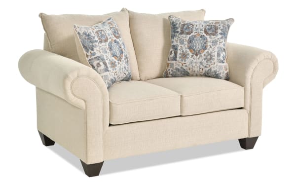 Chloe Beige 67'' Loveseat in transitional style from Chloe Living collection, featuring beige polyester fabric, rolled arms, tapered dark wood legs, coil springs, and two patterned accent pillows.