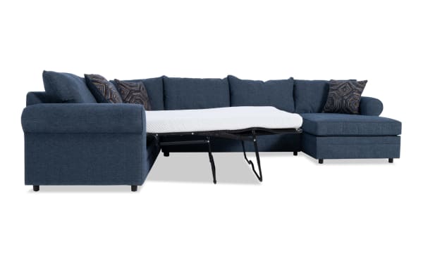 Juno Denim 142'' 4 Piece Right Arm Facing Sleeper Chaise Sectional in blue polyester fabric with transitional style, featuring a pull-out gel memory foam mattress and patterned accent pillows.