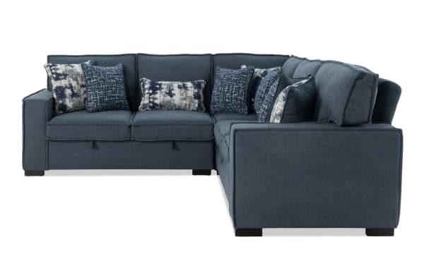 L-shaped sectional sofa in dark blue fabric with plush cushions and patterned throw pillows, featuring modern design and sturdy block legs.