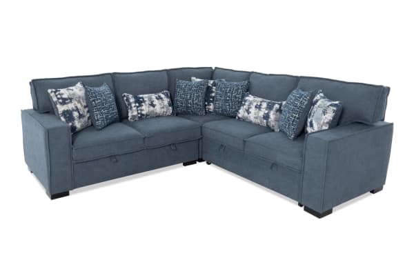 Blue fabric sectional sofa with L-shape design, featuring multiple patterned throw pillows in blue and white tones, modern style.